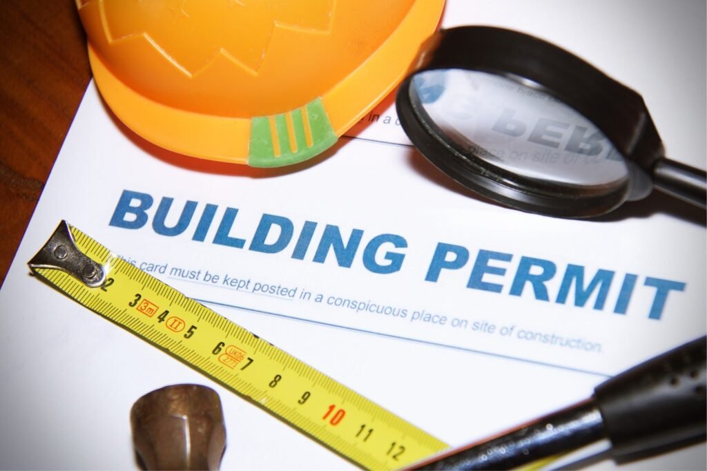 Building permit with hard hat, tape measure, and magnifying glass